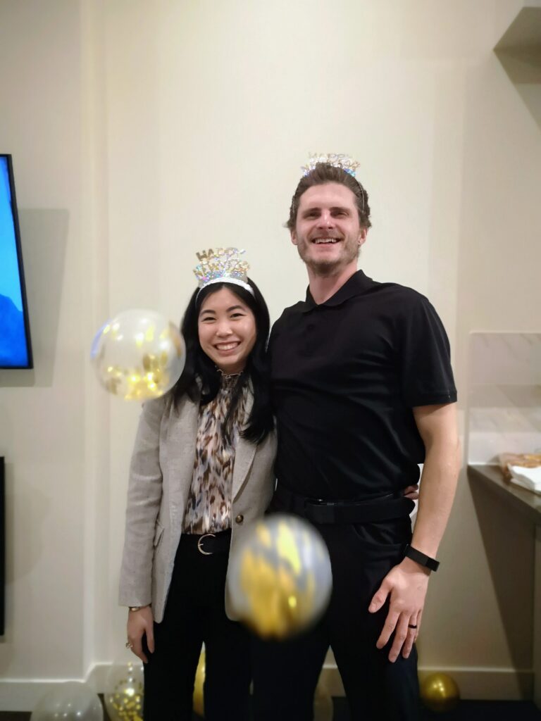 Two people posing for a picture at a party with balloons in the background.
