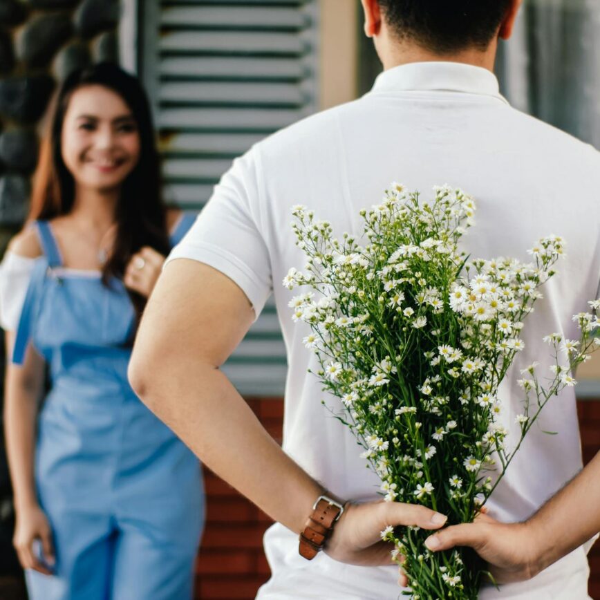 man holding baby s breath flower in front of woman standing near marble wall