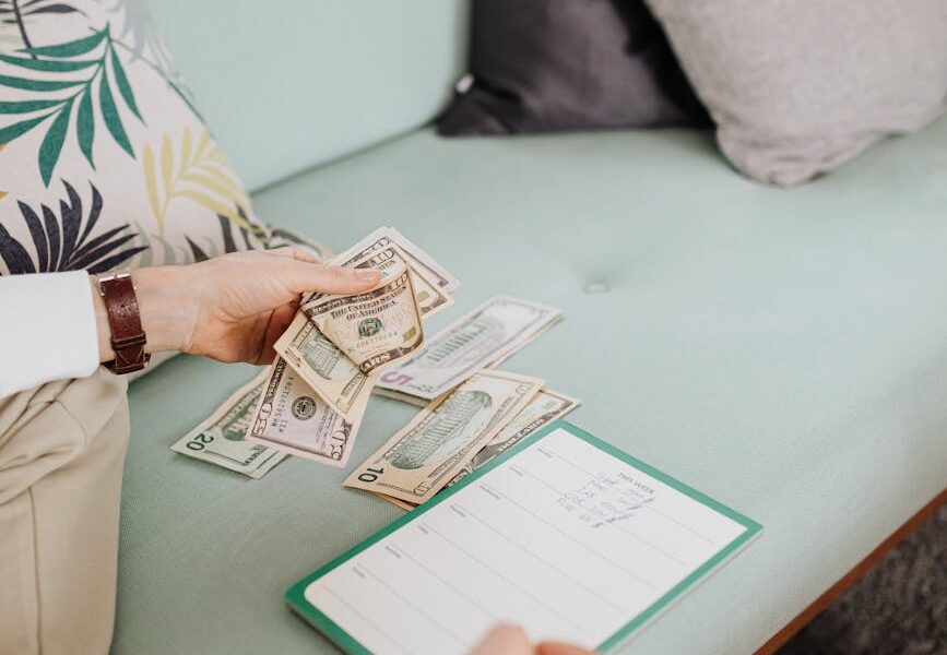 person writing on paper while holding money